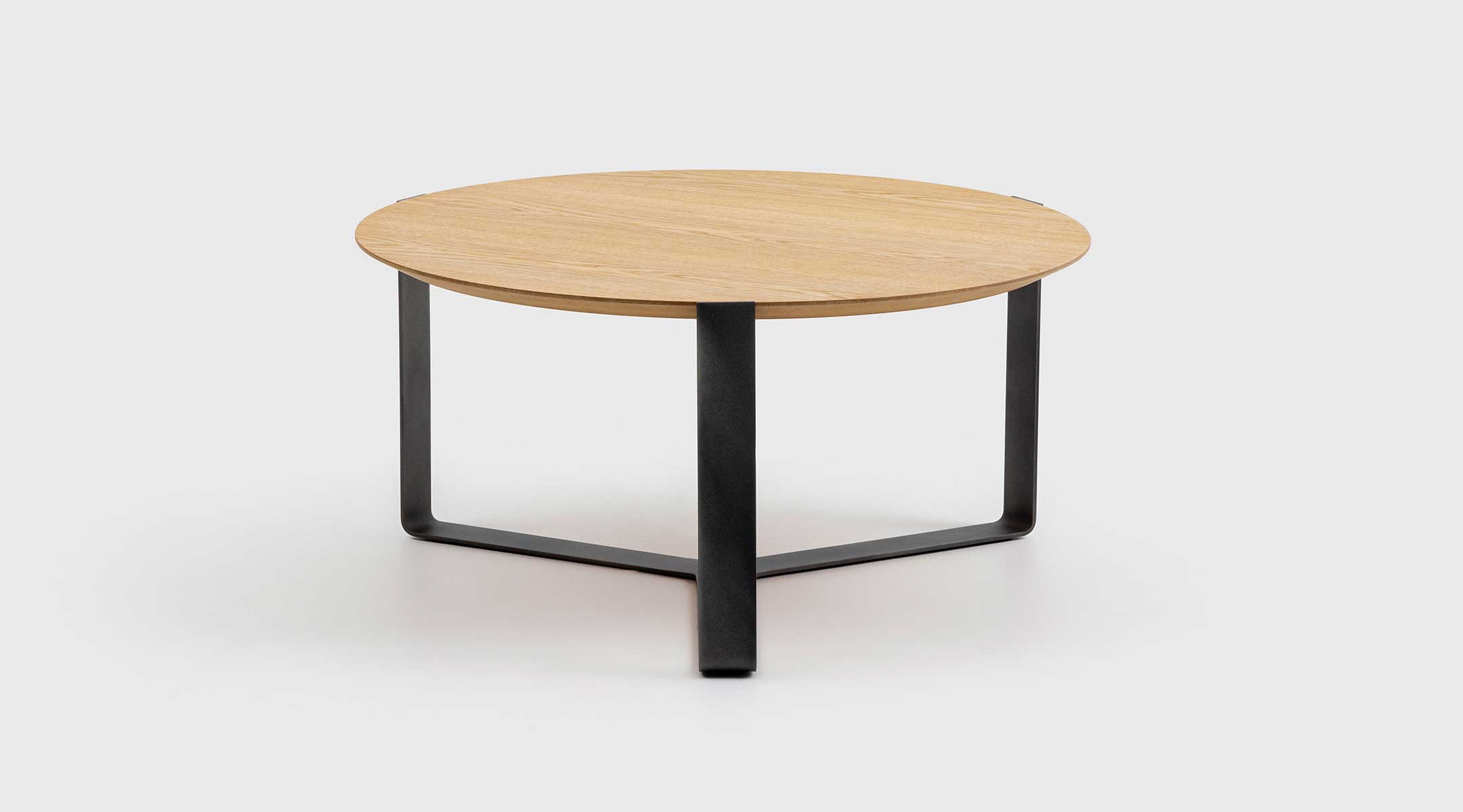 Mesa de centro Guren de Mimma Gallery con tablero redondo de nogal y base triangular de forja, diseño elegante y contemporáneo para salones minimalistas.