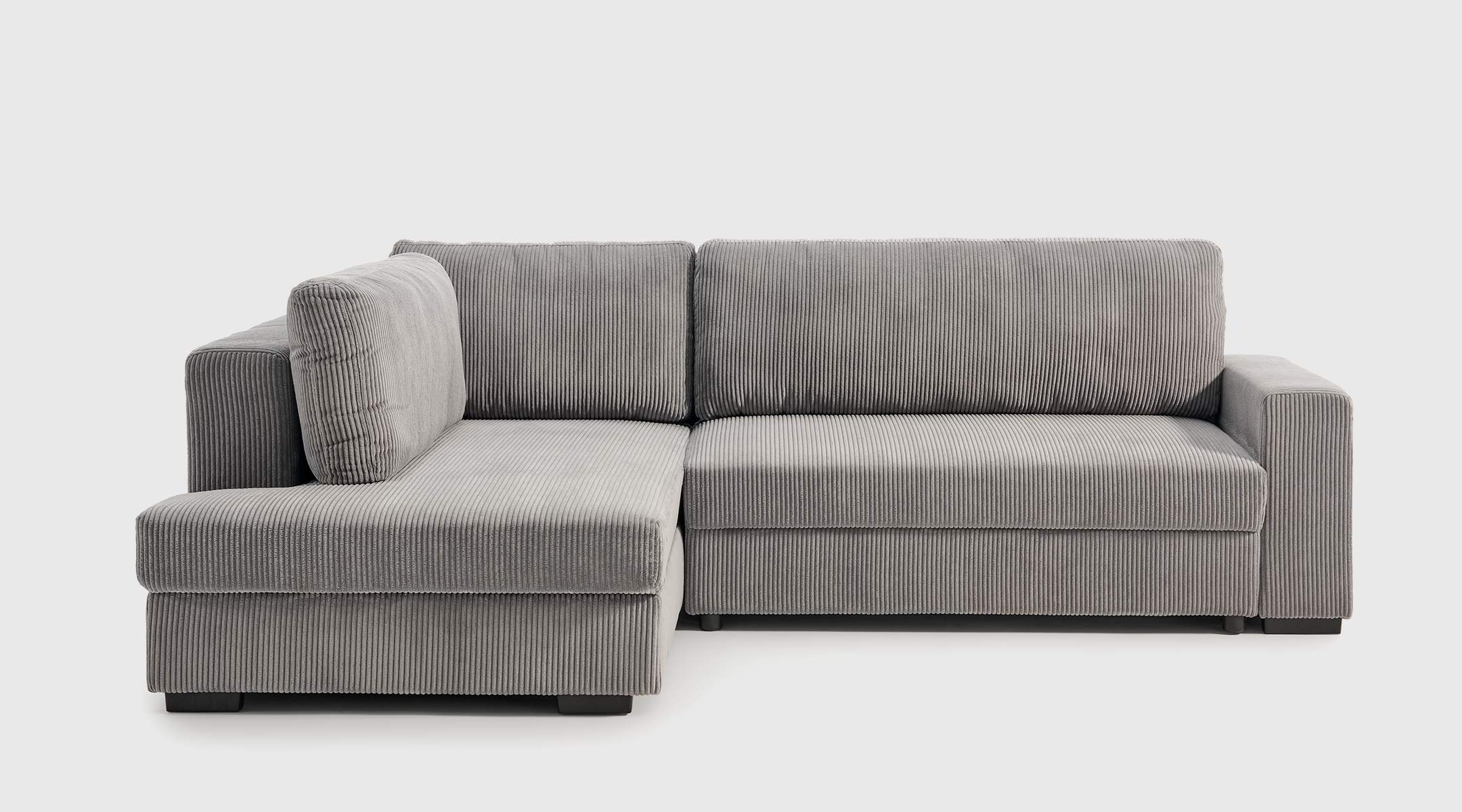 Sofá Cama Atemporal - Sistema Cigüeña y Almacenaje Sofá cama Atemporal abierto con sistema cigüeña, arcón en la chaise longue y estantería integrada en el brazo.