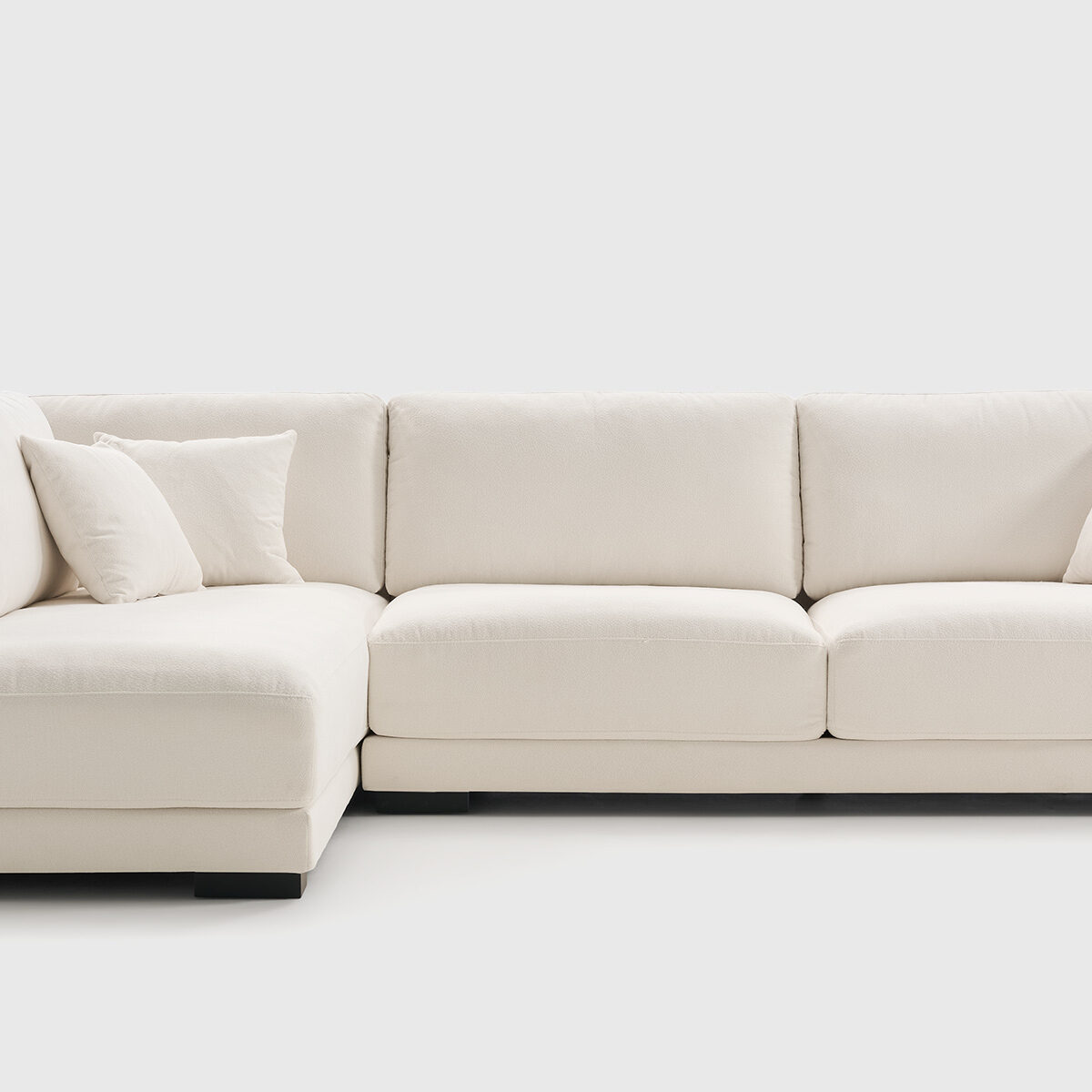 Sofá rinconera Giorno derecha tapizado en tela Hari color blanco, con diseño envolvente y cojines decorativos